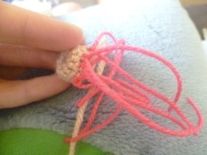 Sew lengths of pink wool to the inside edge and knot them in place.